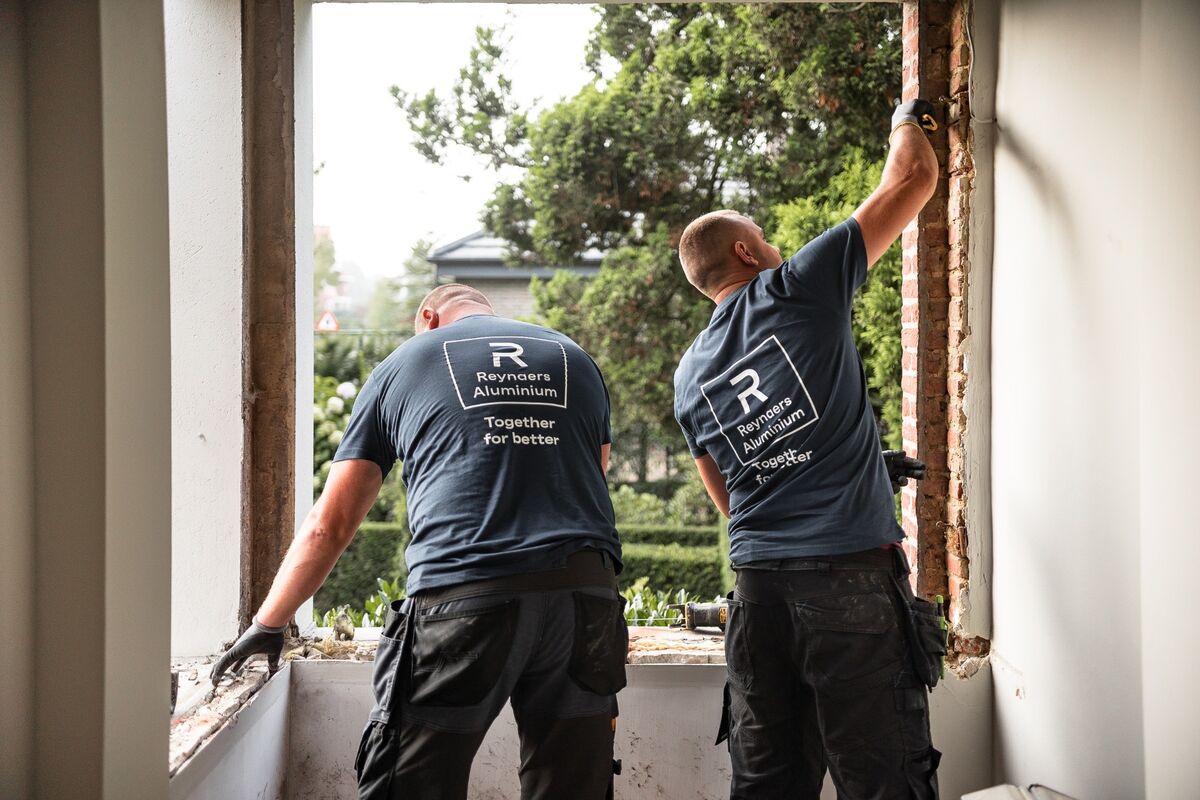 Zwei Monteure von Reynaers Aluminium demontieren alte Fenster vor Ort.