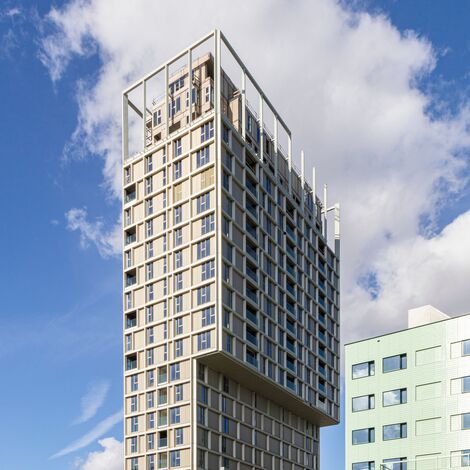 Beigefarbenes Hochhaus mit vielen Fenstern in der Innenstadt.