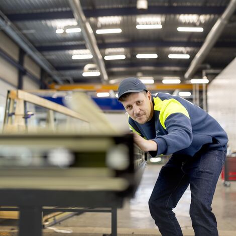 Verarbeiter richtet Fensterprofile aus, während er Sicherheitsausrüstung trägt.