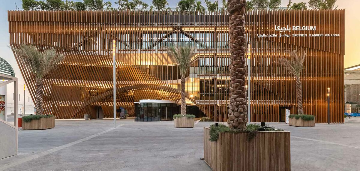 Front view of the Belgian Pavilion with green roof and palm trees.