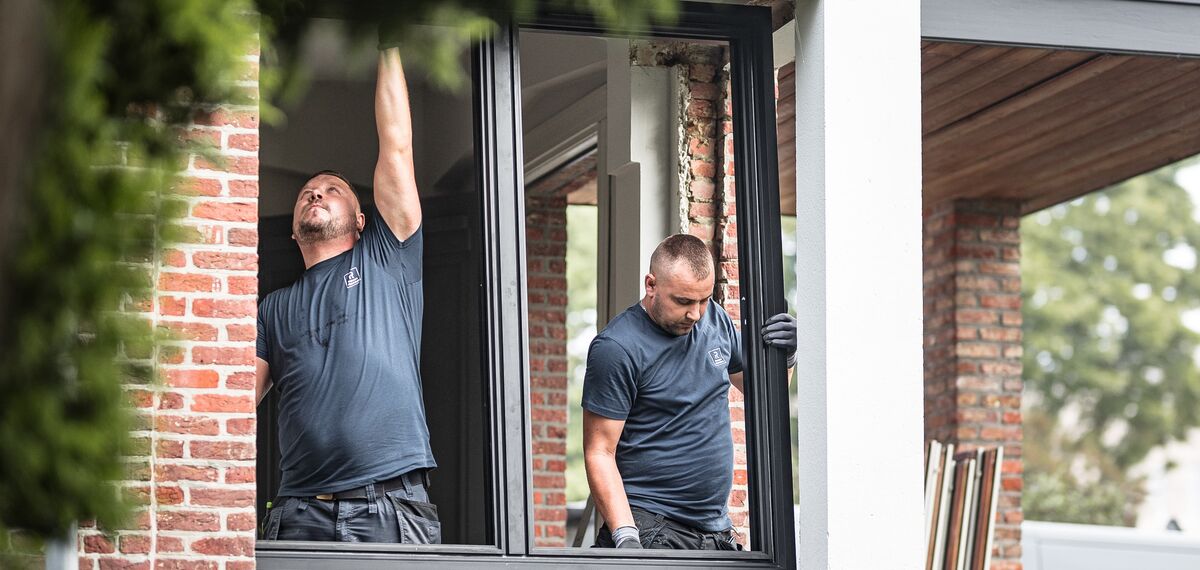 Zwei Installateure platzieren neue Aluminiumprofile in einem renovierten Haus.