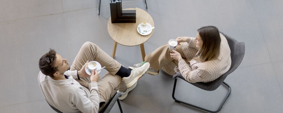 Draufsicht auf Mann und Frau, die an einem Tisch sitzen und Kaffee trinken.