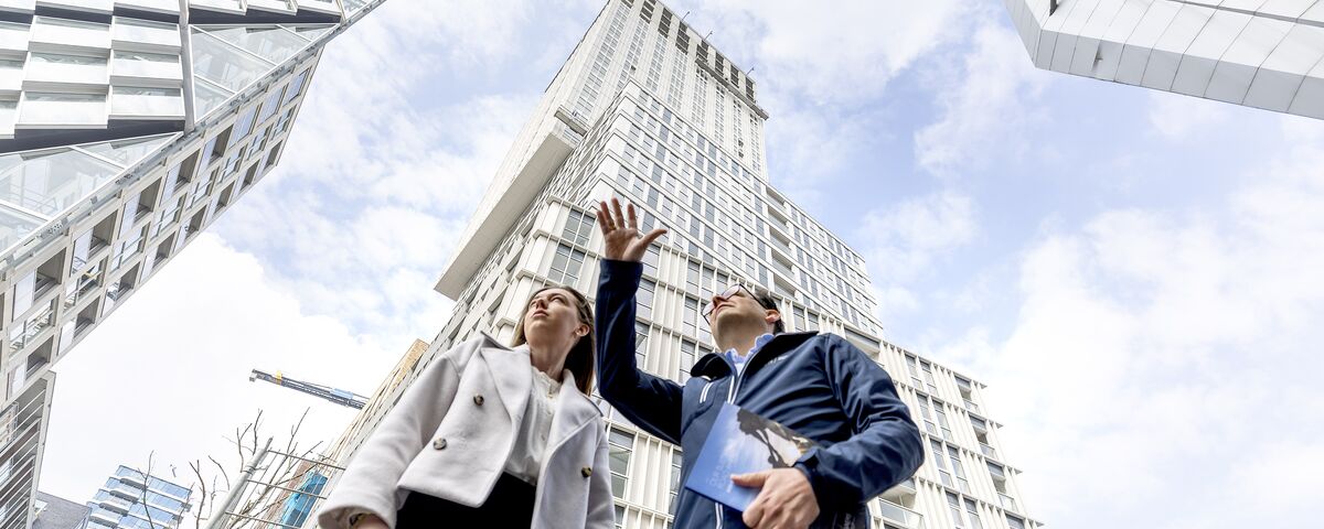 Mann und Frau vor dem Wolkenkratzer zeigen in den Himmel