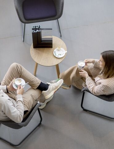 Draufsicht auf Mann und Frau, die an einem Tisch sitzen und Kaffee trinken.