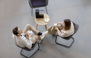 Draufsicht auf Mann und Frau, die an einem Tisch sitzen und Kaffee trinken.