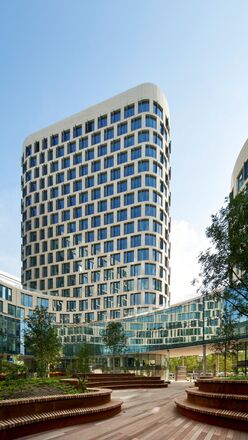 Futuristisches weißes Bürogebäude mit Bäumen daneben.